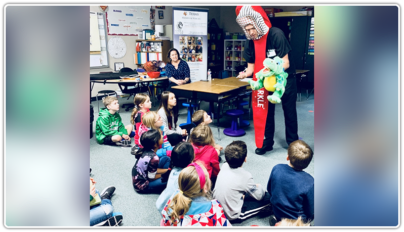 Dr. Hinkle in toothbrush costume talking to kids