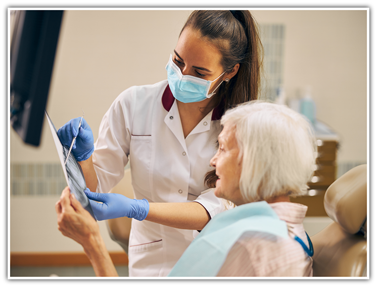 Dental team member showing X ray to older female patient