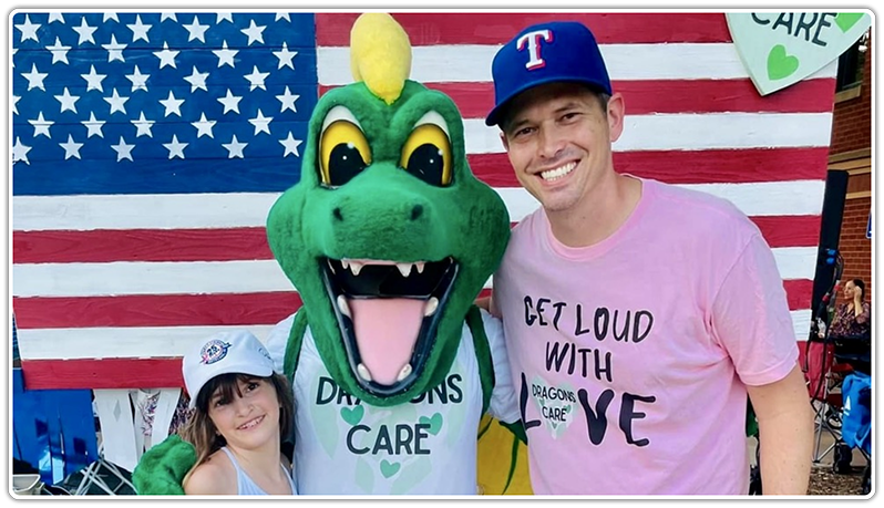 Man and little girl smiling with dragon mascot