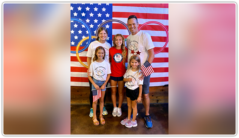 Family smiling in front of American flag
