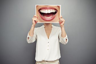 Woman holding up enlarged photo of smile