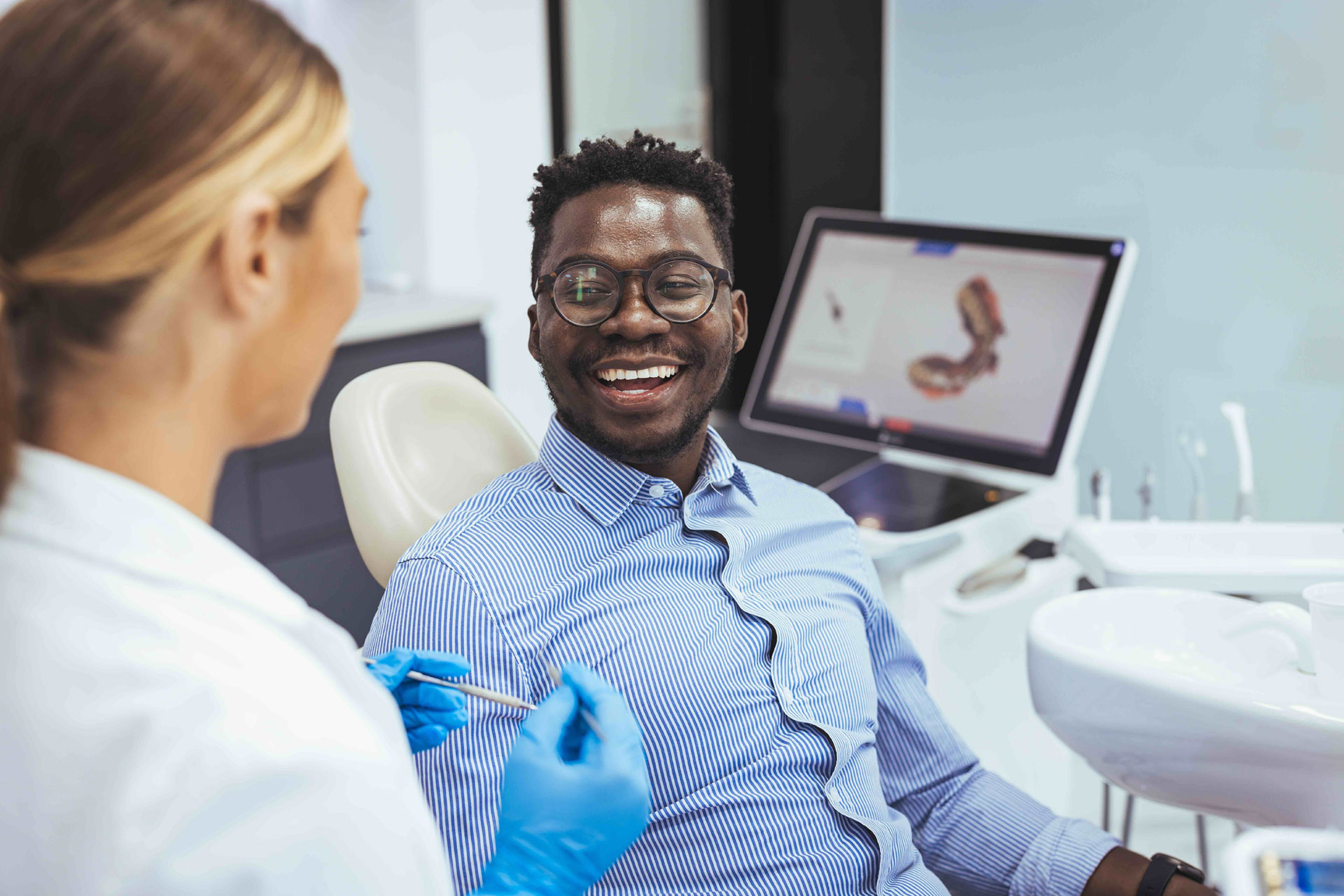 Smiling man in dental chair talking to female dentist