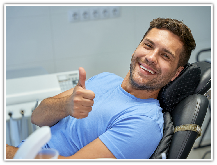 Man sitting back in dental chair giving thumbs up