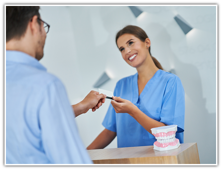 Female dental team member taking card from patient