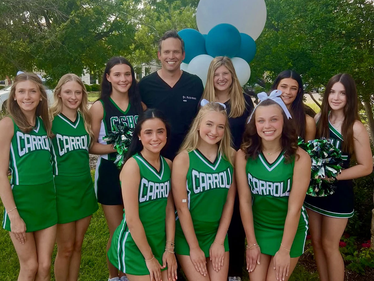 Dr. Hinkle and wife with cheerleader team at ribbon cutting event