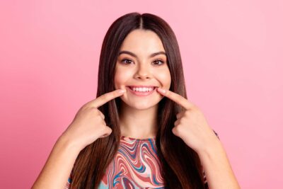 Woman pointing to her smile.