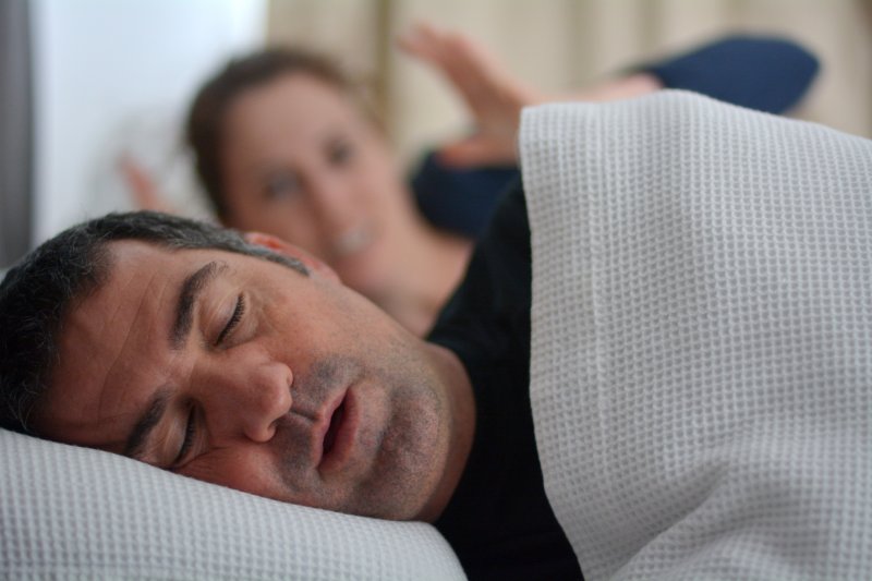 A sleeping man experiencing sleep apnea
